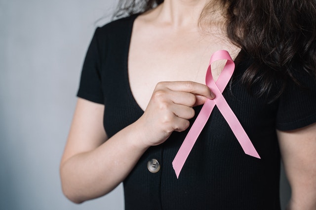 Person holding a pink breast cancer awareness ribbon