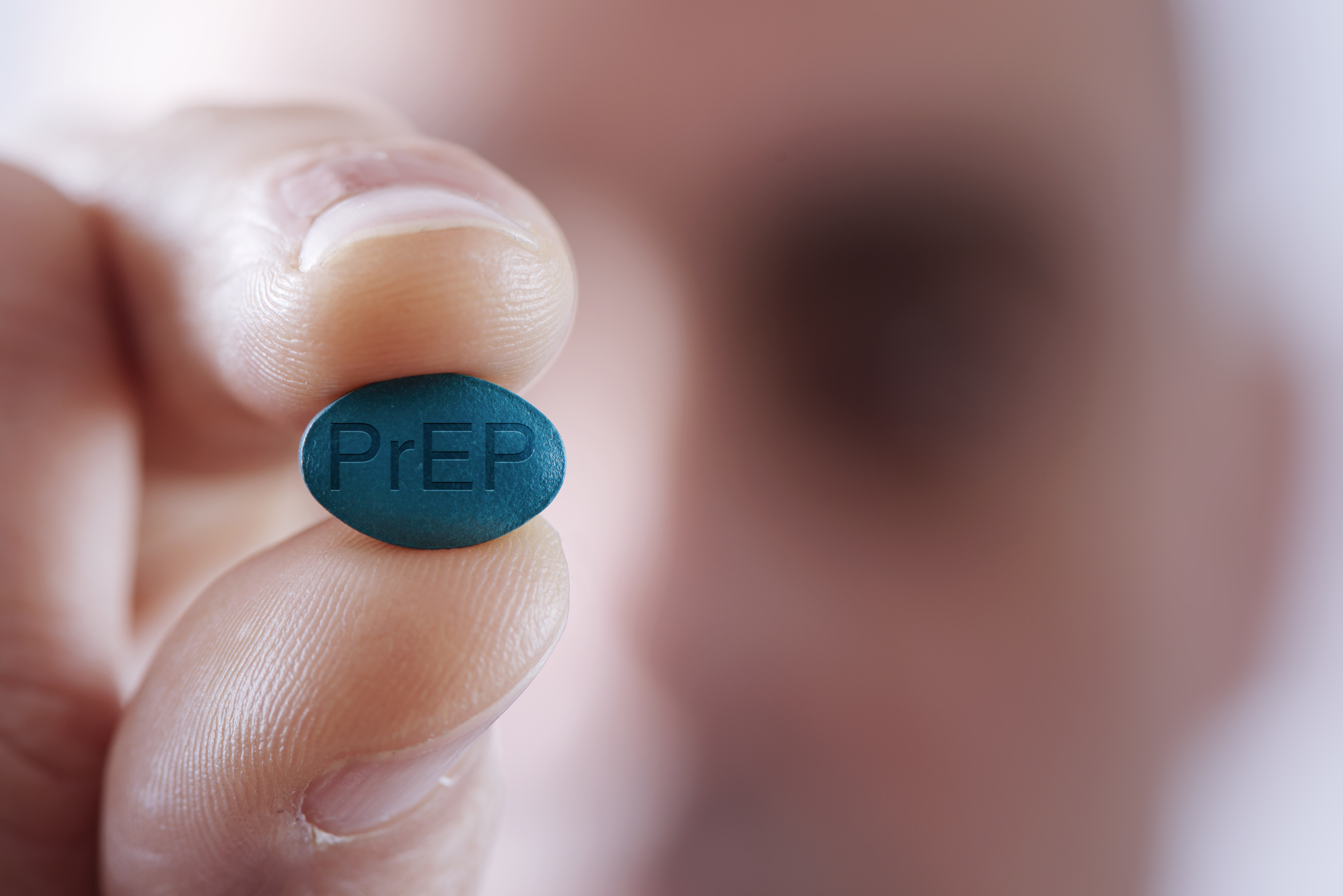 Person holding a PrEP pill up to the camera