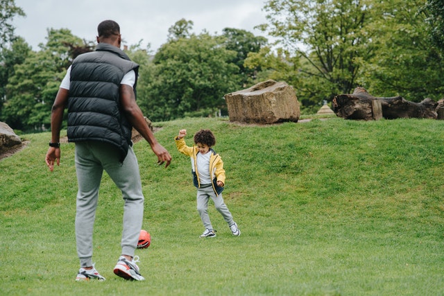Man playing soccer in a field with a boy