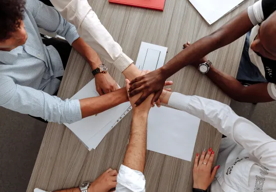 Aerial picture of hands together over a table to signify teamwork