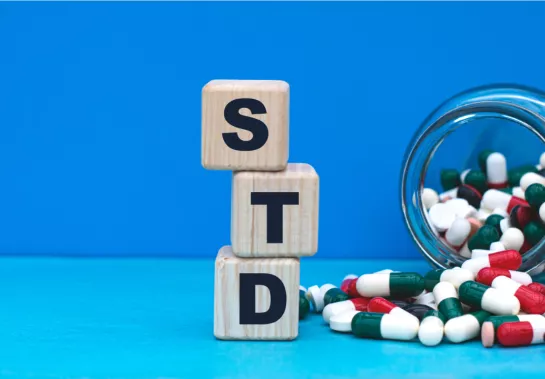 blocks spelling out STD next to a spilled bottle of pills