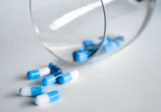 Antibiotic pills spilling from a glass