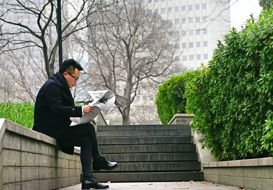 Man reading a newspaper outside
