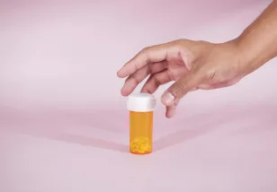 Hand reaching out to pick up a prescription drug bottle