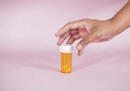 Hand reaching out to pick up a prescription drug bottle