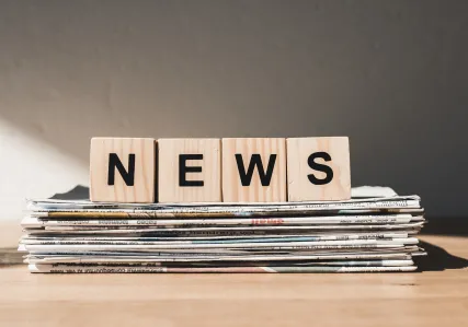 wooden blocks on newspaper stack spell news