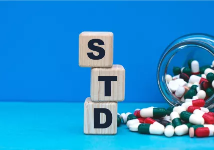 blocks spelling out STD next to a spilled bottle of pills