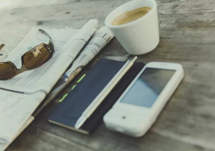 Phone, tablet, newspaper, and coffee